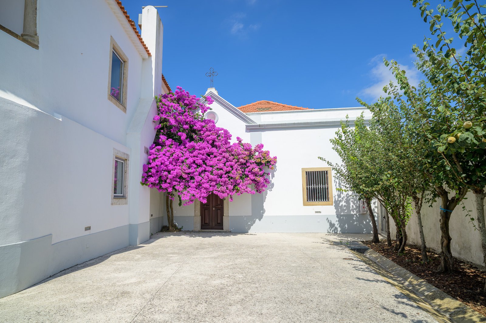 The courtyard and chapel entrance at Quinta do Boiro, with bougainvillea and the bell cross above the door