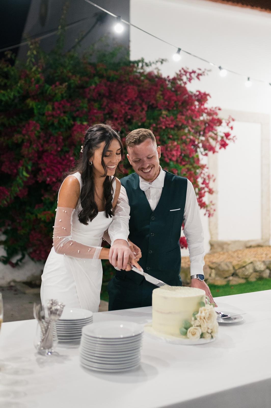 The bride and groom cutting the cake beneath the bougainvillea at Quinta do Boiro